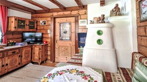 A cozy log cabin interior with a wooden dining table, a television, and a fireplace with decorative animal figures. - Wiesenhof by Interhome (Längenfeld)