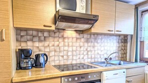 Una cocina moderna con armarios de madera, microondas, estufa, lavavajillas y salpicadero de azulejos.