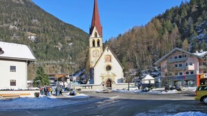 Una iglesia con una aguja alta, rodeada de edificios y un paisaje nevado.