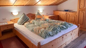 Un dormitorio acogedor con una cama de madera, mesitas de noche, un escritorio y un armario.