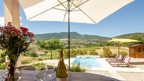 A poolside table with a bottle of wine, glasses, and a vase of flowers. - Les Hauts de Jallia by Interhome (Nyons)