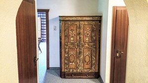 Ein Flur mit einem Holzschrank, einer Tür und einem Fenster mit gemusterten Vorhängen.