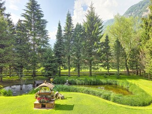 A serene garden with a pond, a wooden bench, and a rustic gazebo. - Garberlashof by Interhome (Längenfeld)