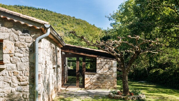 A stone building with a sloped roof and a wooden pergola. - Les Galets by Interhome (Valgorge)