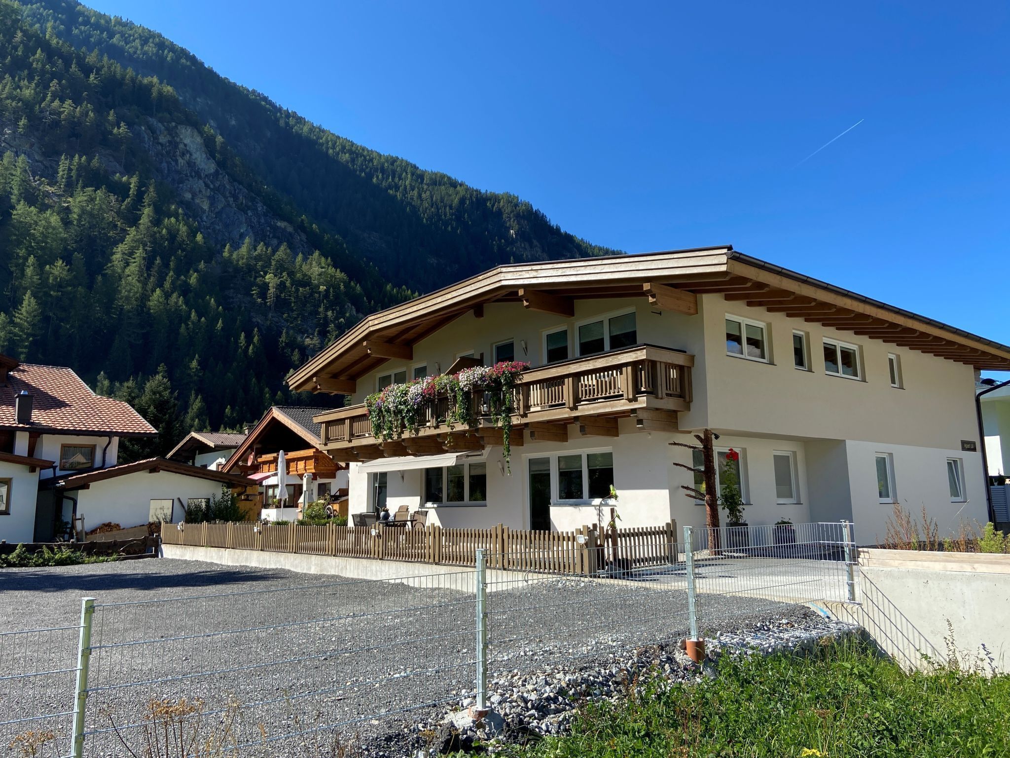Un bâtiment à deux étages doté d’un balcon, entouré d’une zone recouverte de gravier et d’une clôture en bois.