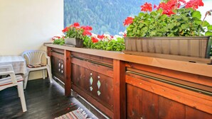 A wooden bar area with potted plants and a view of a mountainous landscape. - Alpenheim Haid by Interhome (Längenfeld)