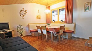 A cozy living room with a sofa, a dining table with chairs, a TV, and a plant. - Alpenheim Haid by Interhome (Längenfeld)