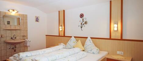 A hotel room with a bed, a nightstand, a sink, and a mirror.