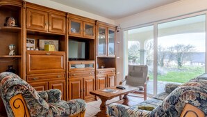 A living room with wooden furniture, a television, and a view of the outdoors. - La Jolie Vague by Interhome (Baubigny)