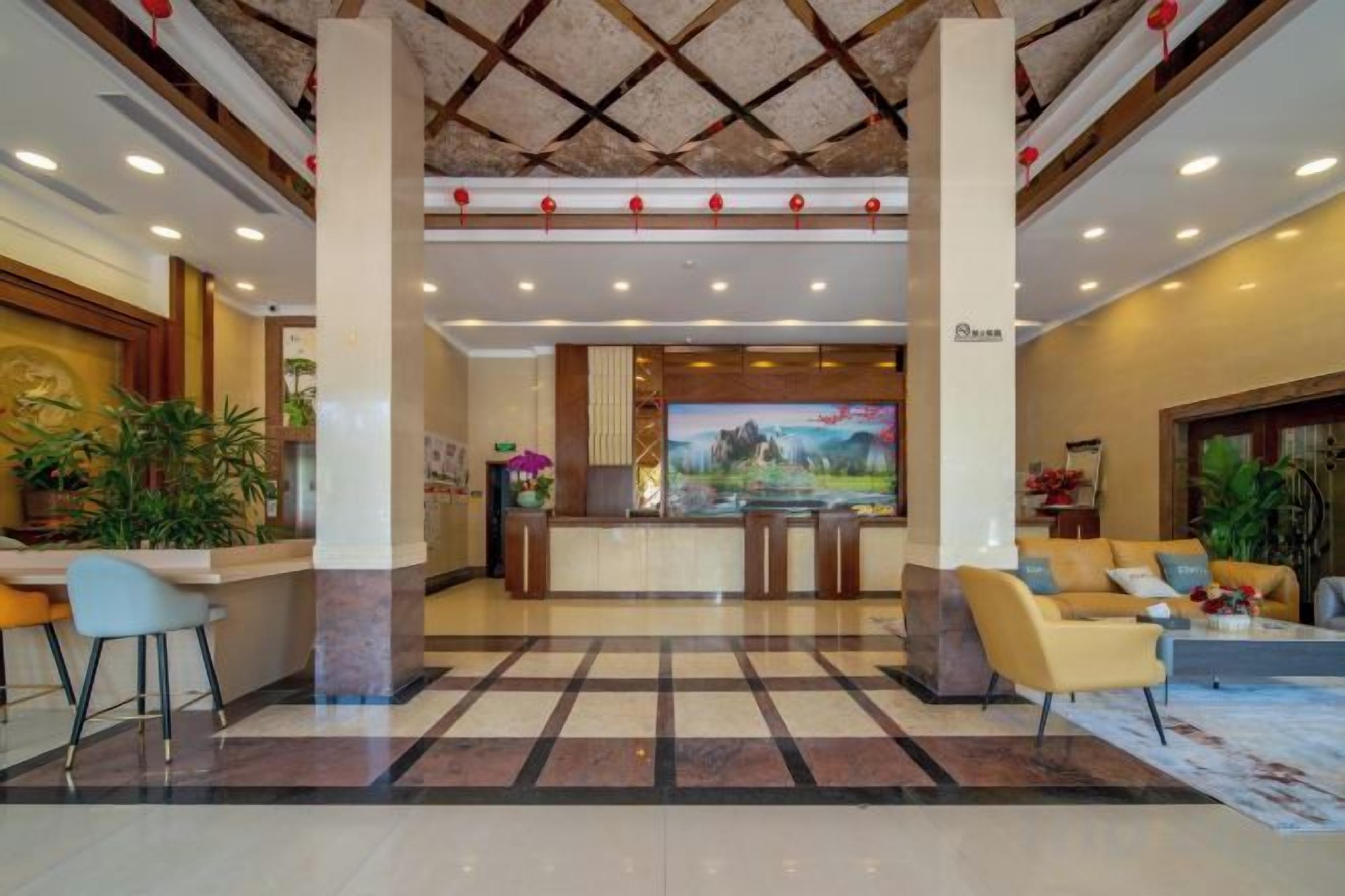 Un vestíbulo de hotel con mostrador de recepción, área de descanso y un cuadro grande en la pared.