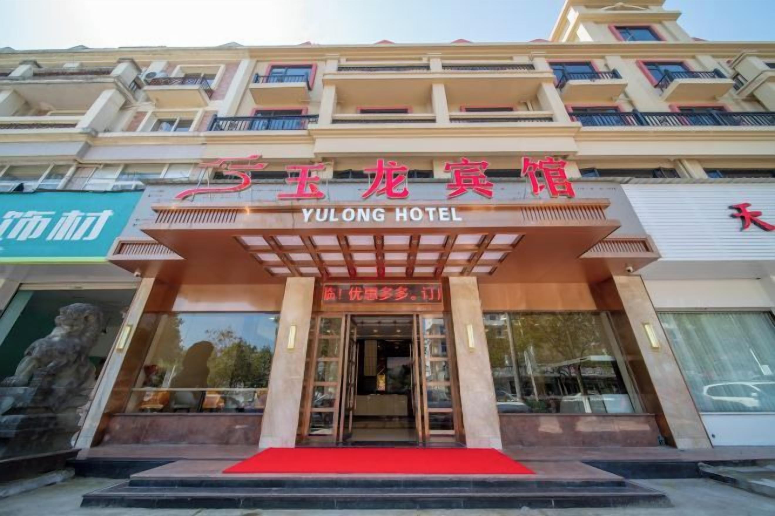 A hotel entrance with a red carpet, a signboard with hotel name, and a staircase leading to the entrance.