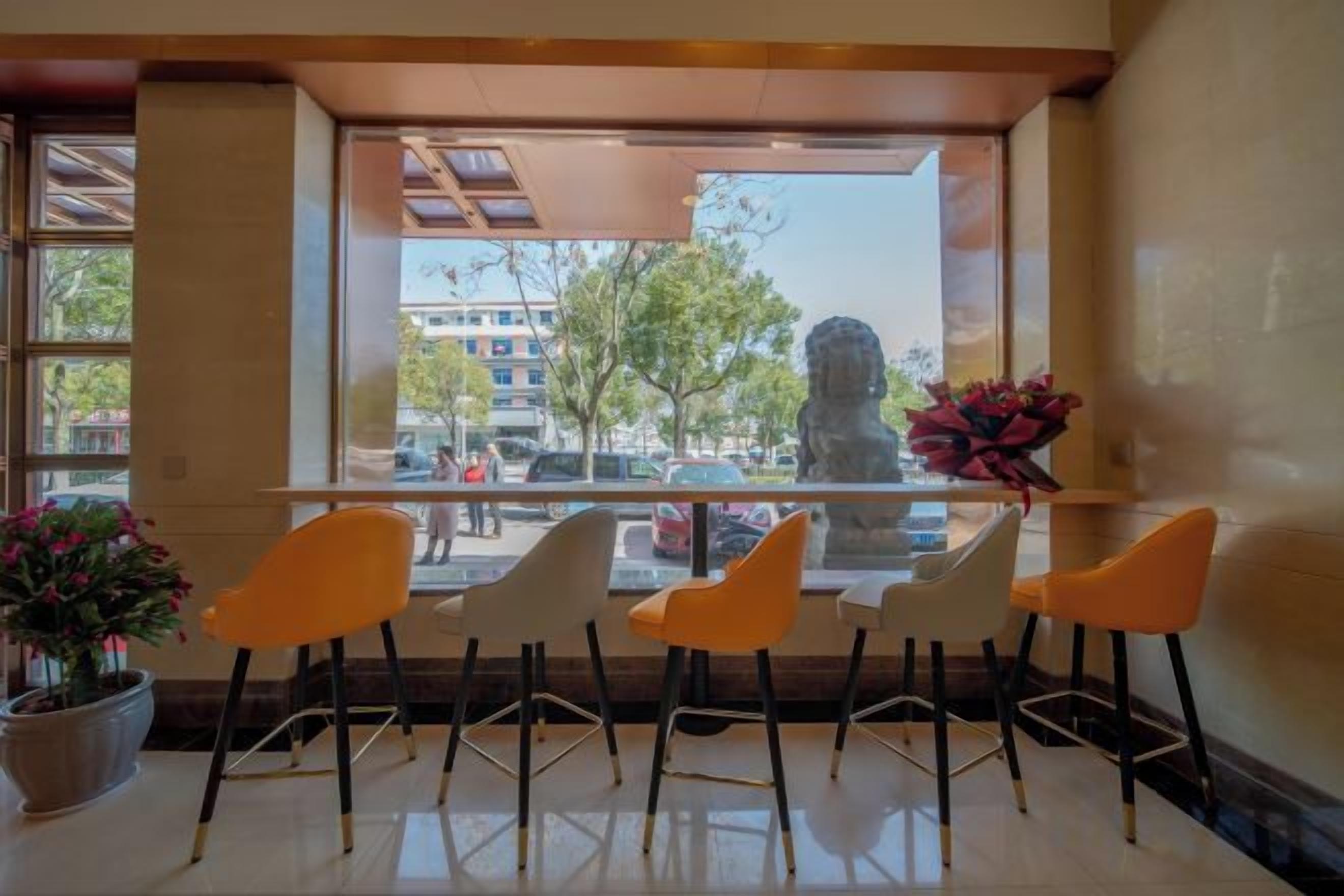 A hotel lobby with a seating area, a large window, and a statue.
