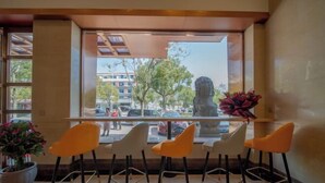 A restaurant with a view of the street, a statue, and a potted plant. - Yulong Hostel (Xianju)