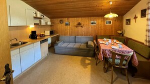 Eine kleine Küche mit Essbereich, Holzwänden und einer gemütlichen Sitzecke.