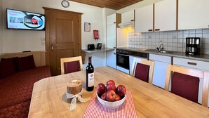 Eine moderne Küche mit weißen Schränken, einer Holzbalkendecke und einem Essbereich mit Tisch für zwei Personen.