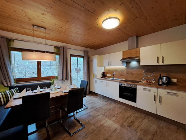 Una cocina moderna con armarios de madera, un comedor con mesa y sillas, y un amplio ventanal con vistas al exterior.