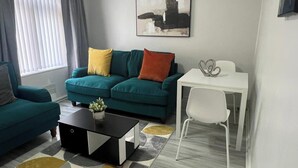 Un salon avec un canapé de couleur turquoise, une table blanche et une table basse.