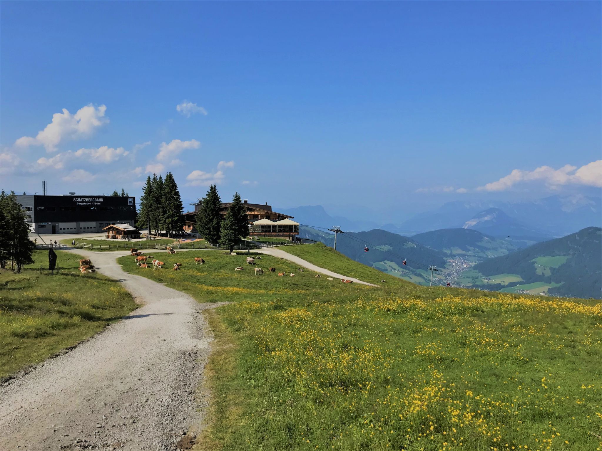 A mountain lodge with a ski lift, a dirt path, and a view of the surrounding mountains.