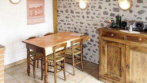 Een eethoek met een houten tafel en stoelen, een stenen muur en een houten kast met een radio.