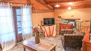 A cozy living room with a wooden ceiling, a television on a table, a sofa, and a cabinet.