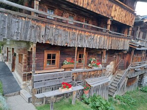Un chalet rustique en bois, doté de plusieurs balcons, de rampes en bois et de jardinières.