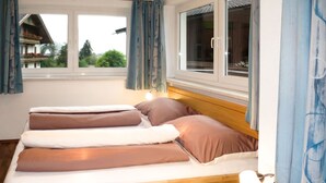 Un lit avec une tête de lit en bois, une table de chevet avec une lampe et une fenêtre avec des rideaux.