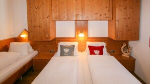 Ein Zimmer mit zwei Betten, Holzschränken und einem Fenster.