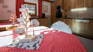 Eine gemütliche Küche mit Holzsäulen, einem Esstisch mit rotem Tischlein und einer Weihnachtsbaumdekoration.