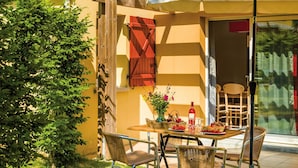 Un patio al aire libre con mesa, sillas y una zona cubierta.