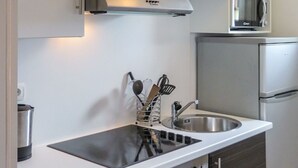 Una cocina compacta con un lavamanos de acero inoxidable, un microondas y un horno empotrado.