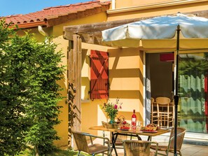 An outdoor patio with a table, chairs, and a covered area.
