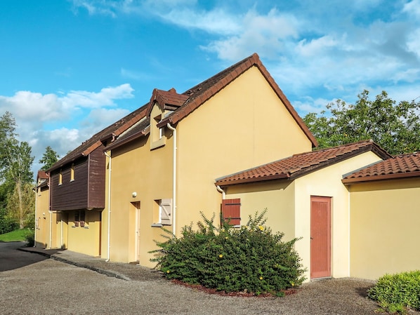 A two-story building with a yellow facade and brown roof tiles.