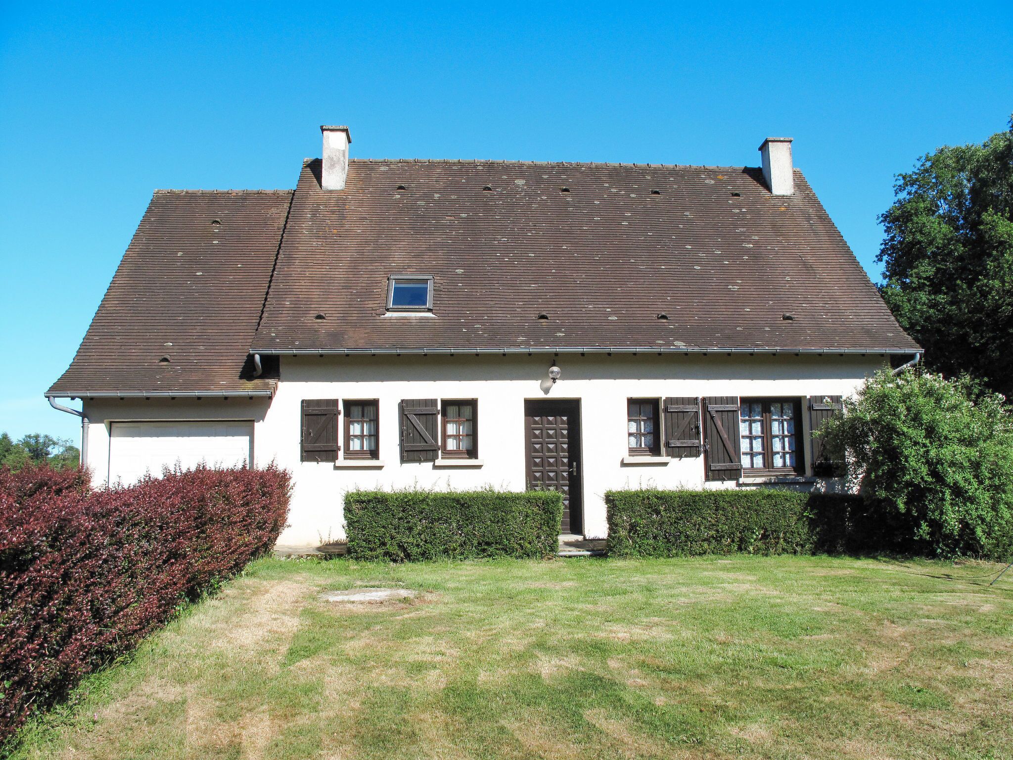 A two-story house with a sloped roof, white exterior walls, and dark shutters on the windows.