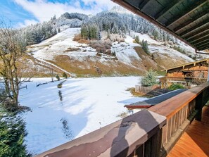 A wooden cabin with a balcony overlooking a snow-covered landscape and a mountain.