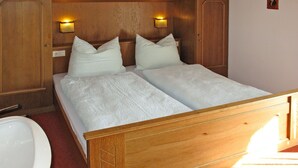 A double bed with a wooden headboard, two wall-mounted lights, and a small portrait on the wall. - Hochwart by Interhome (Mayrhofen)