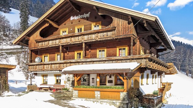 Een houten chalet met een balkon en een bordje waarop 'Schoberhof' staat.