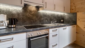 A modern kitchen with white cabinets, a black countertop, a built-in oven, and a stainless steel sink. - Talbach by Interhome (Mayrhofen)
