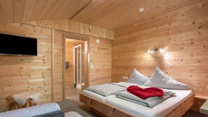 A wooden-paneled bedroom with a bed, a television, and a small sofa. - Talbach by Interhome (Mayrhofen)
