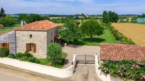 A stone building with a tiled roof, surrounded by a well-maintained garden and a gravel driveway leading to a gated entrance. - Madaillan by Interhome (Prayssas)