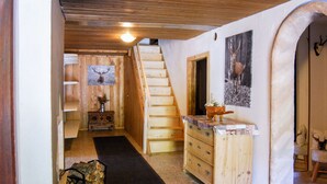 A wooden interior with a staircase, a fireplace, and a deer head decoration.