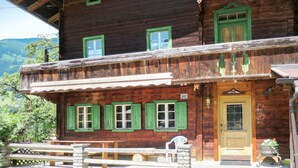 A wooden building with a balcony, a door, and a window with shutters.