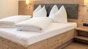 Een slaapkamer met een houten bed, wit beddengoed en twee wandlampen.