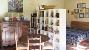 A room with a wooden table and chairs, a bookshelf, a bed with a patterned bedspread, and a rustic wooden cabinet. - Marquefabe by Interhome (Labretonie)