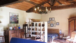 A rustic room with a wooden ceiling, a blue sofa, a bookshelf, a bed with a patterned bedspread, and a wooden cabinet. - Marquefabe by Interhome (Labretonie)