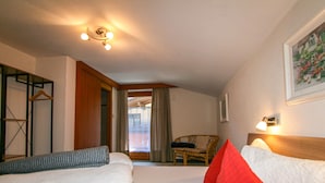 Una camera d'albergo con due letti, una sedia, un armadio e un quadro appeso al muro.