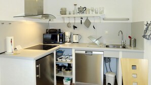 Una cocina compacta equipada con microondas, cafetera y un refrigerador pequeño.