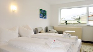 Habitación de hotel con una cama grande, dos sillas, una mesita redonda y una ventana con vistas al exterior.