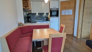 Uma cozinha compacta com uma mesa de madeira e assentos acolchoados vermelhos.