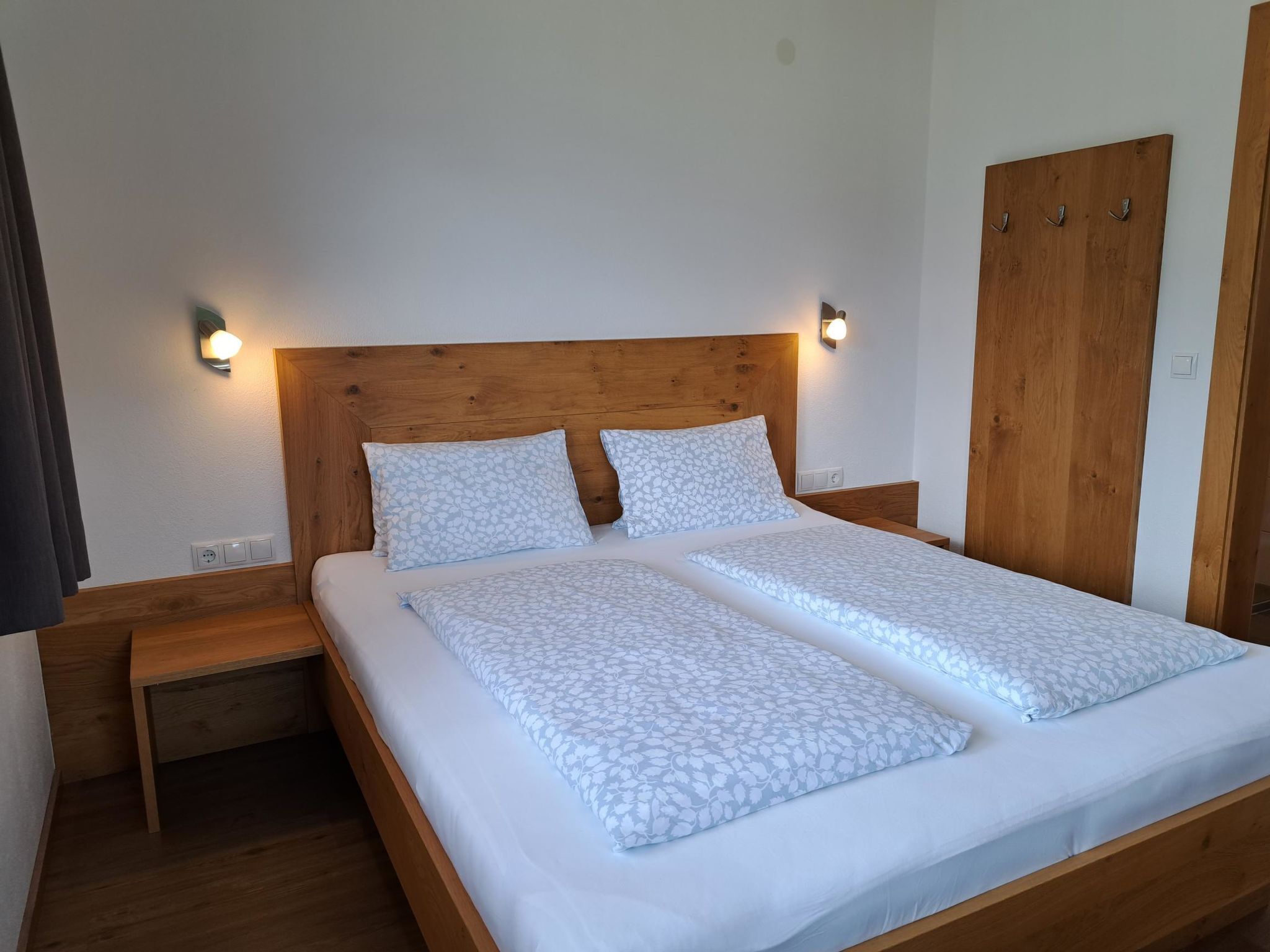 A double bed with a wooden headboard, two bedside tables, and a wardrobe.