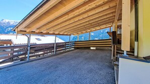 Un'area esterna coperta con pavimento in legno e ringhiera in metallo, affacciata su un paesaggio montuoso.